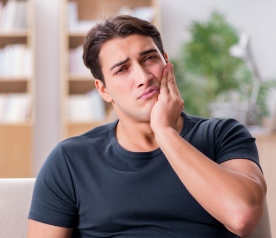 Man holding his cheek and wincing in pain