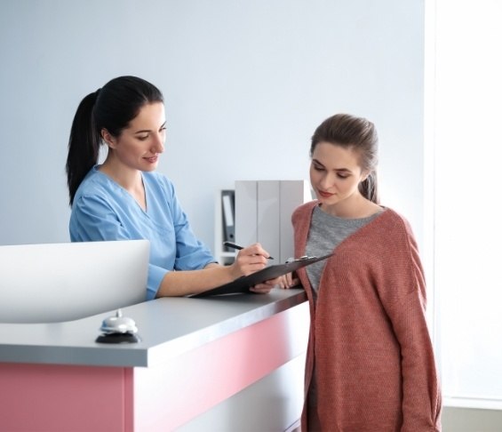 Dental team member handing a clipboard to a patient