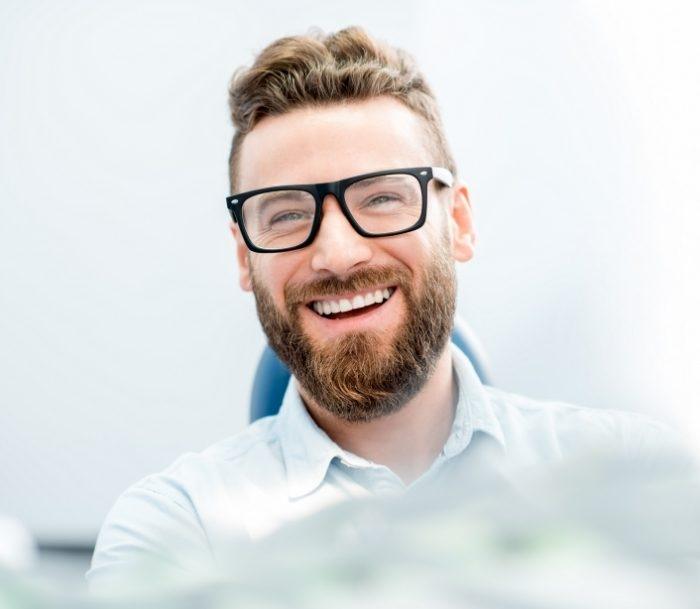 Bearded man smiling in dental chair after endodontic retreatment in Paramus