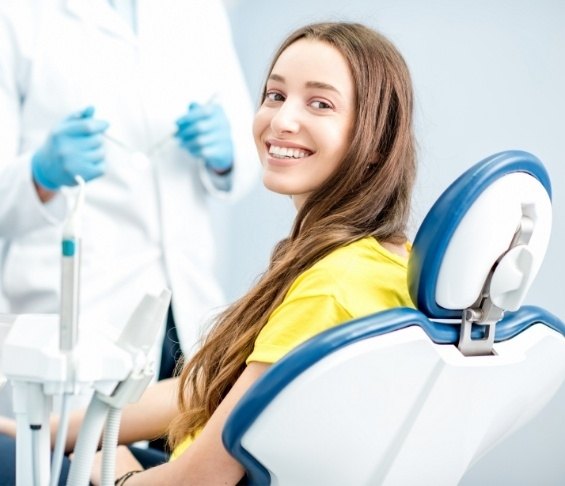 Woman in yellow blouse smiling in dental chair