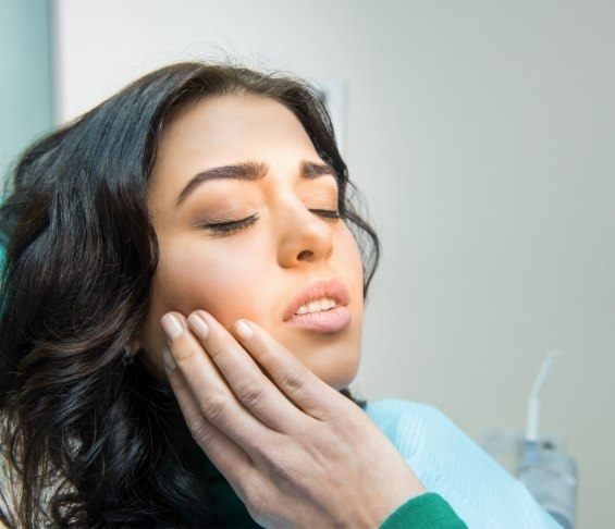 Dental patient holding her face in pain