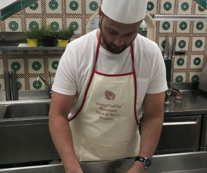 Doctor Forghani wearing chef hat and apron while cooking