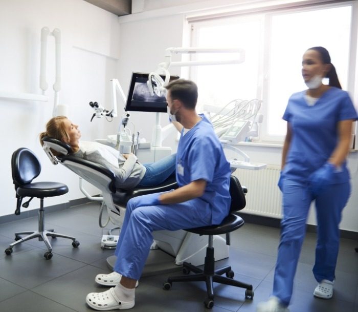 Woman in dental chair talking to endodontic team member in Paramus