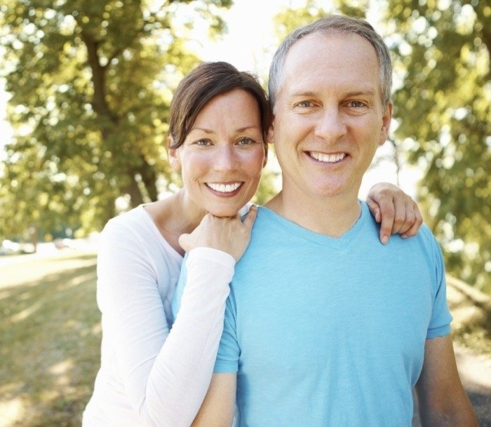 Older man and woman smiling in forest