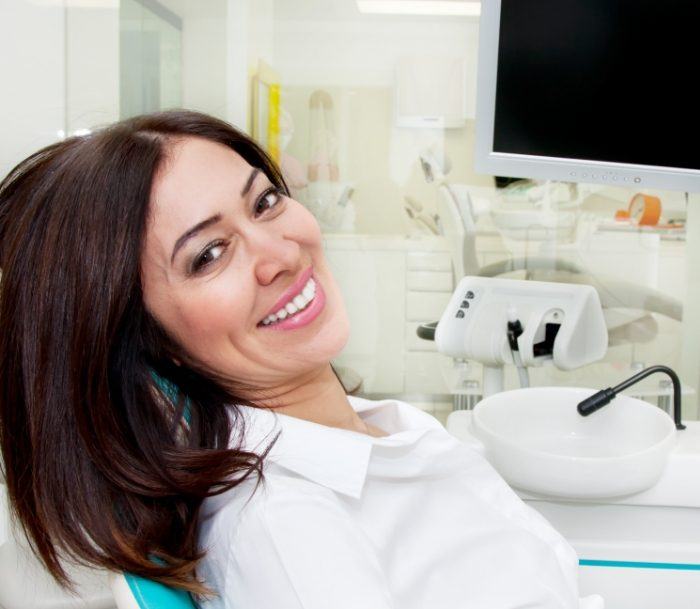 Smiling woman leaning back in dental chair after root canal treatment in Paramus