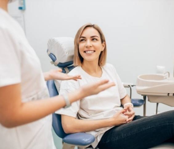 Woman smiling while listening to her dentist talk